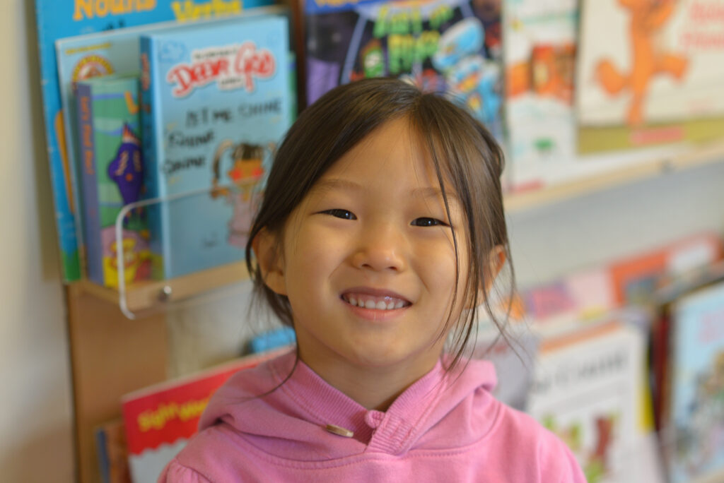 Smiling child in a library setting.