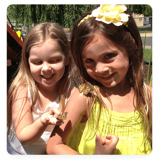 Girls smiling with butterflies on hands.
