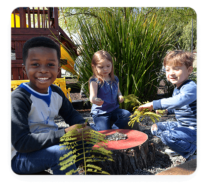 Children playing outdoors with leaves and stones.