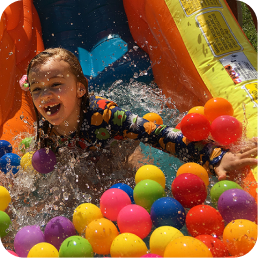 Child playing in colorful ball pit outdoors.