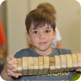 Child holding wooden blocks, smiling at camera.