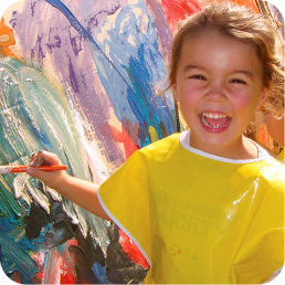 Child joyfully painting with vibrant colors.