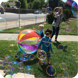 Children surrounded by soap bubbles on grass