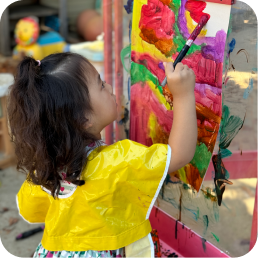 Child painting colorful artwork on easel.