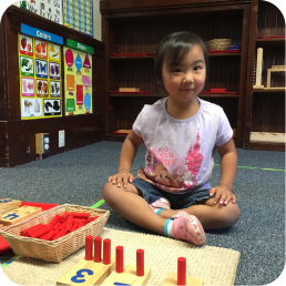 Girl arranging red counting pegs on mat