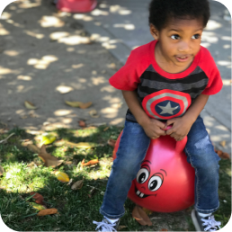 Child playing on a red bouncing ball.