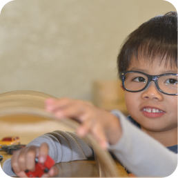 Child playing with toy car on track.