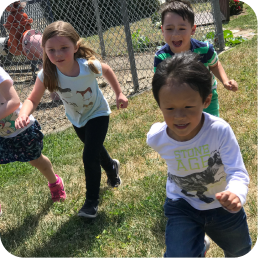Children running and playing outside on grass.