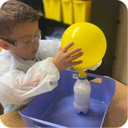 Child inflating balloon with science experiment.
