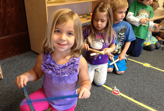 Children playing musical instruments in classroom.
