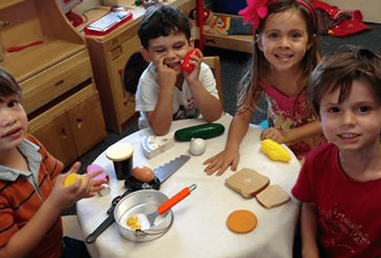 Children playing with toy kitchen food items.
