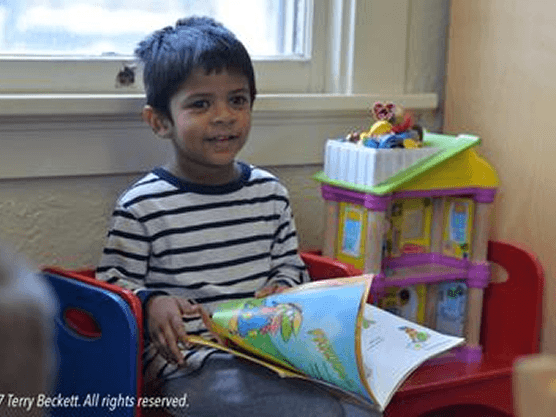Child reading a book in classroom.
