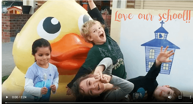 Children posing with large rubber duck sculpture.