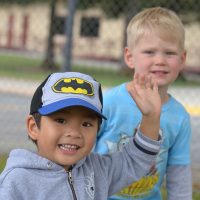Two smiling children waving at camera.